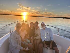 A joyful family enjoys a sunset cruise on a boat, capturing a memorable moment together as the sun sets over the water.