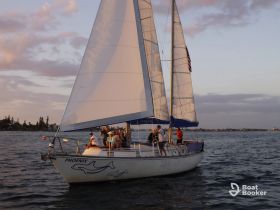 A lively group enjoys a sailing experience aboard the 'Phoenix' during a beautiful sunset, making for a perfect evening on the water.
