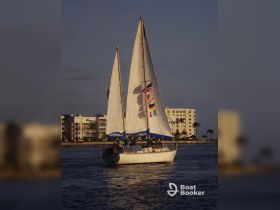 A beautiful sailing vessel named 'Phoenix' glides through the water at sunset, with guests enjoying the scenic views — perfect for memorable sailing adventures.