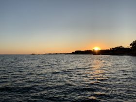 A serene sunset view over the water, showcasing the beautiful coastline — perfect for peaceful evening boat rides.