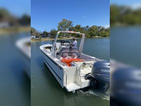 A speedboat navigates through calm waters with a captain at the helm, showcasing the vessel's sleek design and functionality.