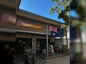 A view of Tipplers Licensed Cafe featuring Australian flags and a welcoming entrance, ideal for visitors looking to enjoy local cuisine.