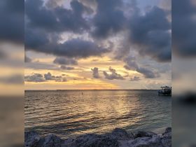 A stunning sunset over the water, with clouds reflecting vibrant colors — a perfect backdrop for evening boat trips or coastal adventures.