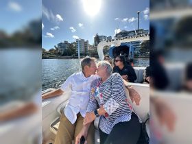 A couple shares a romantic kiss aboard a boat, surrounded by scenic waterfront views — a perfect moment for love on the water.