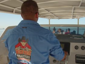 A captain navigates a charter boat with passengers enjoying the scenic views — perfect for a memorable day on the water.