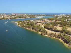 A stunning aerial view of a picturesque coastline with lush greenery and clear waters, showcasing the beauty of the area — perfect for exploring by boat.