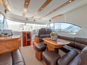 A beautifully designed interior of a boat featuring comfortable seating and a well-equipped helm, perfect for relaxing or navigating the waters.