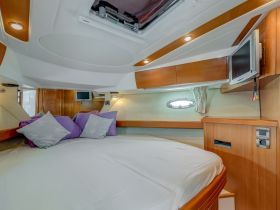 Cozy cabin interior featuring a comfortable bed with decorative pillows, perfect for relaxing on a boat getaway.