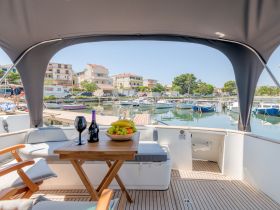 A cozy interior view of a boat featuring a dining area with a fruit bowl and wine, perfect for relaxing moments on the water.