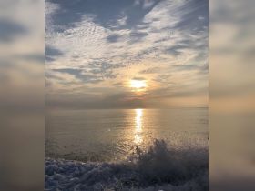 A stunning sunset over calm ocean waters, with reflections shimmering on the surface — a perfect moment for relaxation and appreciation of nature's beauty.