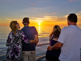 A group of friends enjoys a stunning sunset on the water, creating a perfect backdrop for romantic moments and cherished memories.