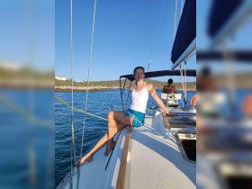 A woman enjoys a sunny day on a sailboat, showcasing the perfect blend of relaxation and adventure on the water.
