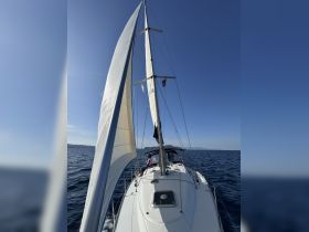 A serene moment aboard a sailboat, with a guest enjoying the ocean breeze while sailing under clear skies — perfect for a relaxing day on the water.