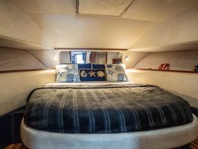 Cozy cabin interior featuring a comfortable bed adorned with decorative pillows, perfect for relaxing on a boat getaway.