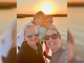 A group of friends captures a joyful selfie against a stunning sunset backdrop while enjoying their time on the water — perfect for memorable outings and celebrations.