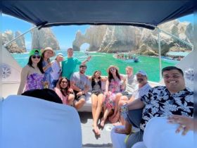 A lively group enjoys a sunny day on a boat in Cabo San Lucas, capturing the joy of their adventure against a stunning coastal backdrop.