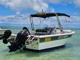 A sleek speedboat named 'FULMINE' is docked in shallow waters, showcasing its modern design and powerful outboard motor against a picturesque backdrop.