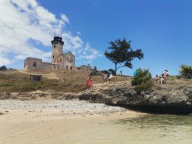 Visitors explore a historic lighthouse on a scenic beach, enjoying a day of adventure and relaxation in the sun.