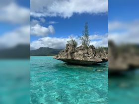 A stunning view of a rocky outcrop surrounded by crystal-clear turquoise waters, showcasing the natural beauty of the coastline.