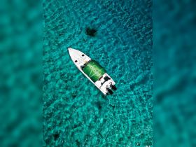 A stunning aerial view of a boat cruising over crystal-clear turquoise waters, perfect for exploring beautiful coastal destinations.