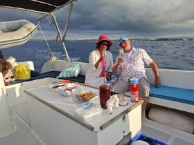 A couple enjoys a toast with cocktails aboard a boat, surrounded by delicious snacks — perfect for celebrating special moments on the water.