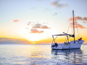 A serene sunset view of a sailboat anchored in calm waters, showcasing the tranquil beauty of evening on the sea.