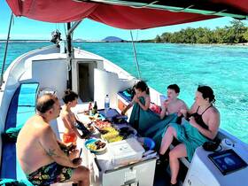 A joyful family enjoys snacks aboard a boat, surrounded by stunning turquoise waters — a perfect day of fun and relaxation on the water.