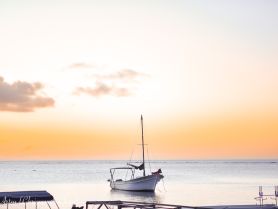 A serene sunset view of a sailboat docked peacefully on calm waters, creating a picturesque scene perfect for tranquil boating experiences.