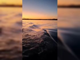 A serene sunset over water, capturing the gentle waves and warm colors of the evening sky. Ideal for showcasing tranquil boating experiences.