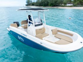 A sleek center console boat cruising through clear turquoise waters, showcasing its spacious seating and stylish design — perfect for day trips and fishing adventures.