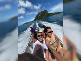 A joyful group enjoys a boat ride, capturing the moment with smiles against a stunning island backdrop — perfect for adventure seekers and island explorers.