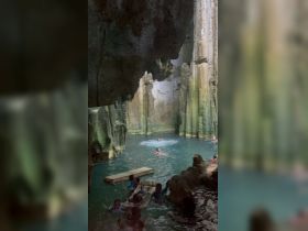 A lively group enjoys swimming in a stunning cave pool, showcasing a unique adventure experience surrounded by natural rock formations.