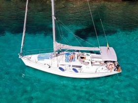 A group enjoys a sunny day on a catamaran, lounging on deck in crystal-clear waters — perfect for a relaxing sailing adventure.
