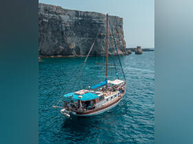 A beautiful sailing boat navigates through crystal-clear waters near stunning cliffs, showcasing a perfect day on the water.