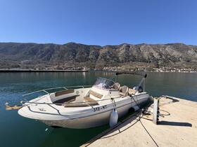 A sleek speedboat docked at a serene harbor, surrounded by stunning mountainous scenery, perfect for a day on the water.
