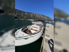 A sleek boat docked at the marina, showcasing its elegant design against a backdrop of stunning mountains and clear blue skies.