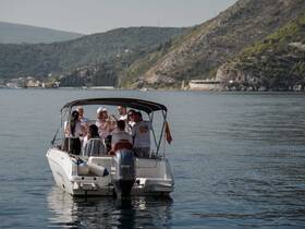 A lively group enjoys a celebration aboard a boat, surrounded by stunning coastal scenery — perfect for memorable outings on the water.