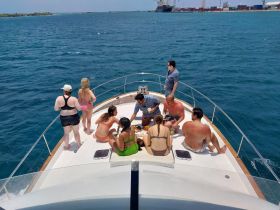 A lively group enjoys a festive gathering on the deck of a yacht, sharing food and drinks while soaking up the sun — perfect for summer celebrations on the water.