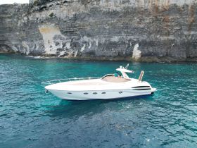 A sleek speedboat glides through crystal-clear waters, showcasing its elegant design against a stunning rocky backdrop — perfect for adventurous outings on the water.