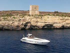 A stunning aerial view of a sleek yacht anchored near a rocky coastline, showcasing the beauty of the Mediterranean landscape.