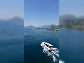 A scenic view of a boat cruising through calm waters, surrounded by stunning mountains — perfect for exploring the beautiful coastline.