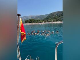 A lively group enjoys a refreshing swim in crystal-clear waters, celebrating a perfect day at the beach — ideal for summer fun and group outings.