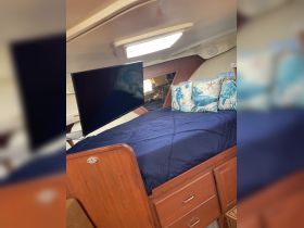 Cozy cabin interior featuring a comfortable bed and a mounted TV, perfect for relaxing on a boat getaway.