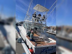 A group of friends relaxes on the deck of a fishing boat at the dock, ready for a day on the water. Perfect for fishing trips and group outings.