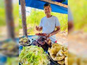 A chef presents a delicious spread of grilled meats, fresh salad, and sides, perfect for a memorable dining experience on the water.