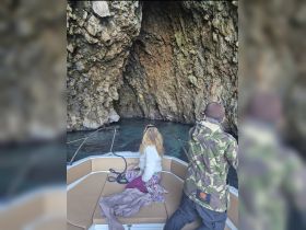 A serene moment aboard a boat as two guests explore a stunning cave, showcasing the beauty of nature and adventure on the water.