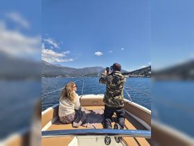 A couple enjoys a scenic boat ride, with one capturing the moment on their phone — perfect for creating lasting memories on the water.