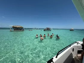 A lively group enjoys a sandbar stop in crystal-clear waters, perfect for swimming and socializing under the sun.