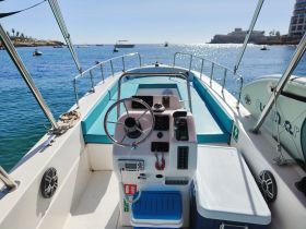 A well-equipped helm area of a boat featuring a steering wheel, console, and comfortable seating, perfect for navigating the open waters.