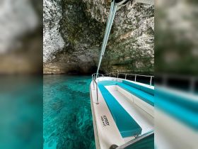 Interior view of a boat with turquoise seating, showcasing a cozy space ideal for exploring stunning underwater caves and clear waters.